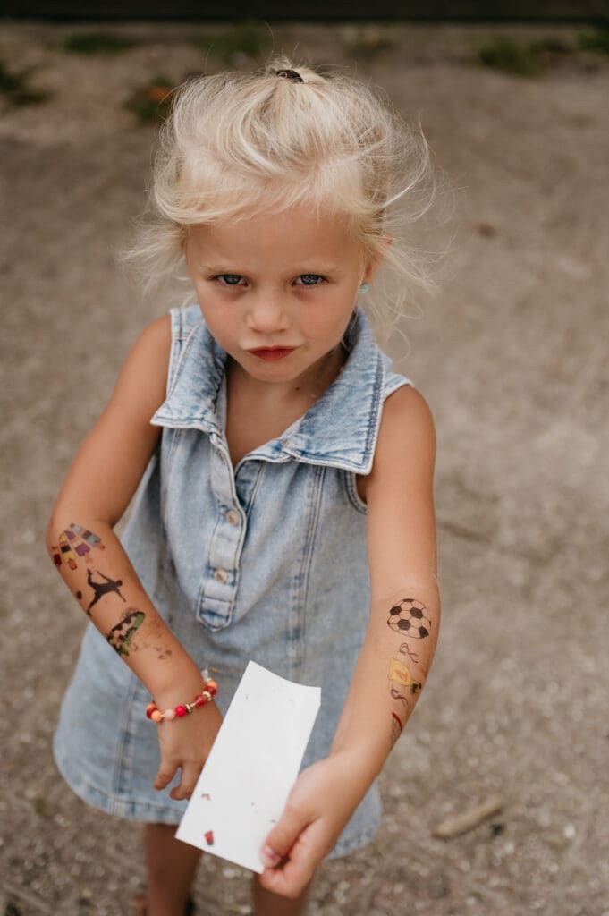 Zonder blokkades en speels: een meisje laat met trots haar plak-tattoos zien aan de gezinsfotograaf.